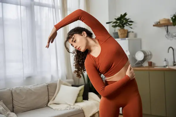 A young woman stretches in her cozy living room, enhancing her well being and vitality. — Stock Photo