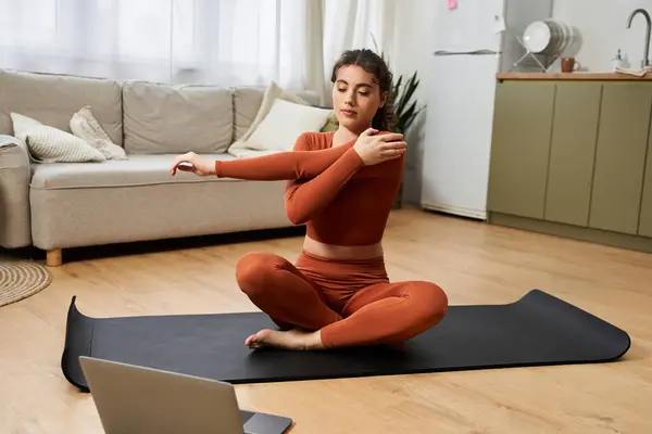 In a warm space, a woman stretches on a mat, prioritizing her well being. — Stock Photo