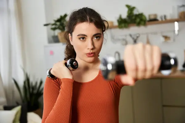 Eine schöne junge Frau macht Krafttraining zu Hause und zeigt ihr Engagement und ihre Fitness. — Stockfoto