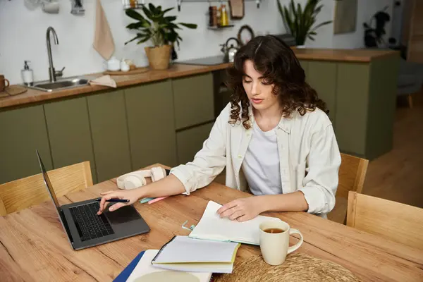 Una joven está absorta en sus tareas en casa, rodeada de suministros creativos y calidez.. - foto de stock