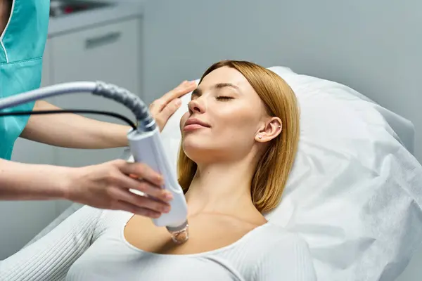 A young woman smiles as a professional performs a skin treatment procedure at a dermatology clinic. — Stock Photo