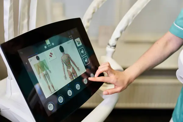 A young medical professional uses a touchscreen to review dermatology procedures. — Stock Photo