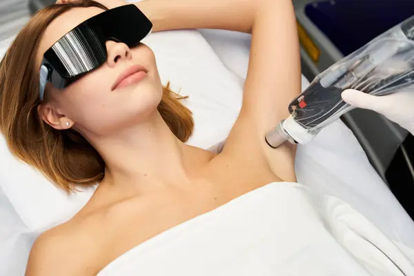 Uma mulher jovem e bonita desfruta de um procedimento de depilação a laser enquanto relaxa em uma clínica. — Fotografia de Stock