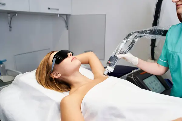 Una giovane donna si rilassa durante la depilazione laser sotto le ascelle in una moderna clinica. — Foto stock
