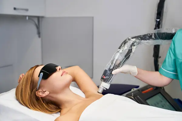 A young woman relaxes during a laser hair removal treatment, ensuring smooth skin results. — Foto stock