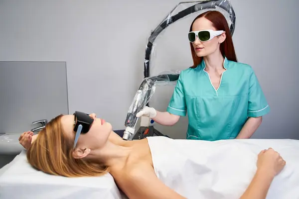 Uma jovem mulher aumenta sua beleza com a depilação a laser em uma clínica moderna. — Fotografia de Stock
