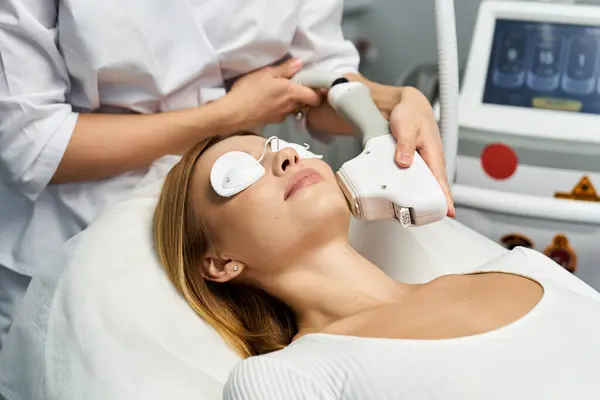 Uma jovem mulher passa por um procedimento de tratamento de pele enquanto relaxa em um ambiente de clínica confortável. — Fotografia de Stock
