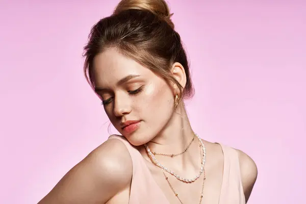 Una joven muestra su elegante atuendo y delicadas joyas con un vibrante telón de fondo rosa. - foto de stock