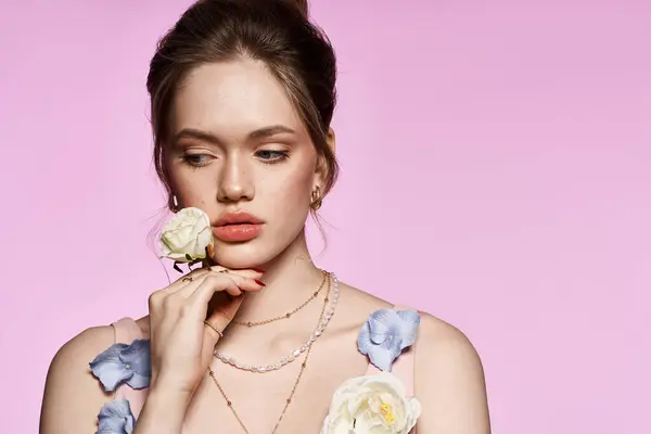 A young woman holds a flower by her face, showcasing chic spring fashion and elegance. — Stock Photo