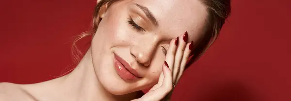 A young beautiful woman smiles softly while posing with one hand near her face in chic attire. — Stock Photo