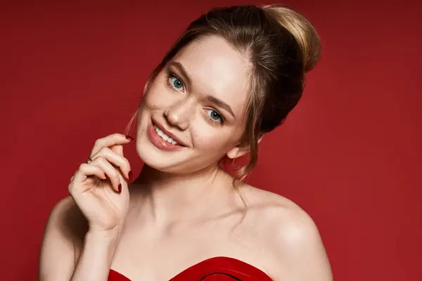 Una joven mujer irradia elegancia con un elegante atuendo de primavera sobre un fondo rojo brillante. - foto de stock