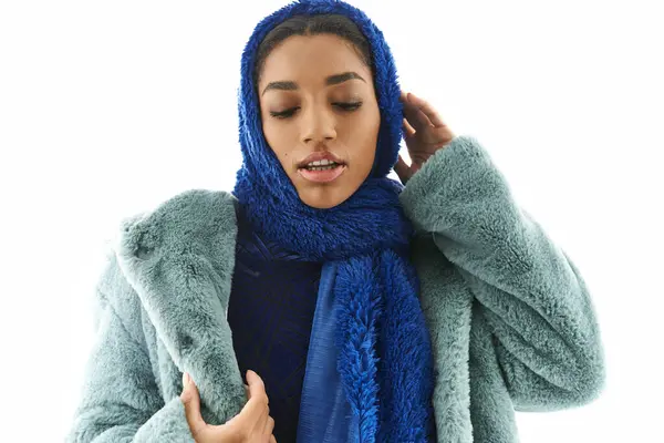 Young woman flaunts chic layers and a vibrant scarf against a bright backdrop. — Stock Photo