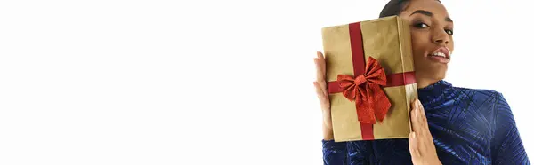 Captivating young woman showcasing chic attire style while playfully holding a gift. — Stock Photo