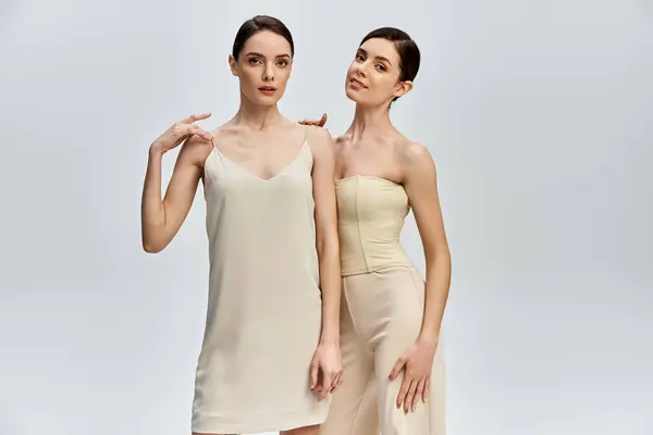 Twin sisters pose gracefully in elegant outfits, showcasing their beauty and connection. — Stock Photo