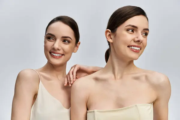 Twins smile together in a joyful portrait, showcasing their close bond in soft lighting. — Stock Photo
