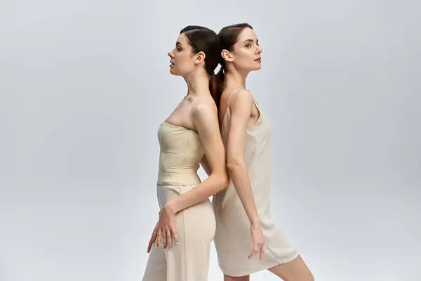 Deux belles sœurs se tiennent dos à dos, soulignant leurs caractéristiques frappantes et leur élégance. — Photo de stock