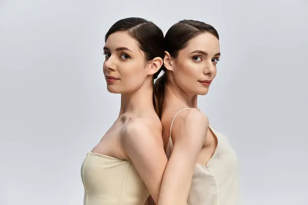 Deux jolies jumelles se tiennent dos à dos, affichant leur beauté saisissante et leur connexion. — Photo de stock