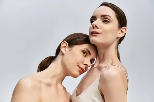 Two beautiful twin sisters elegantly pose together, radiating grace and warmth. — Stock Photo