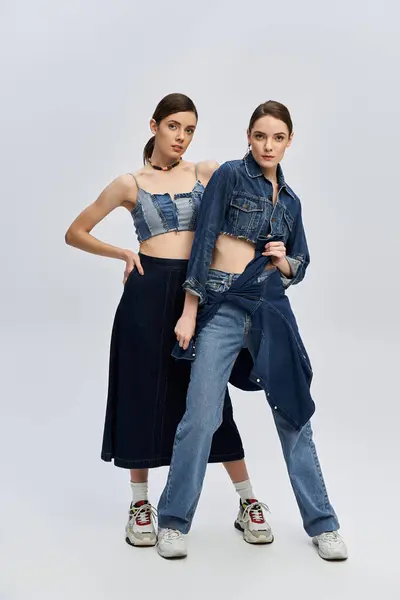 Twins express their individuality through trendy denim outfits, striking playful poses together — Stock Photo