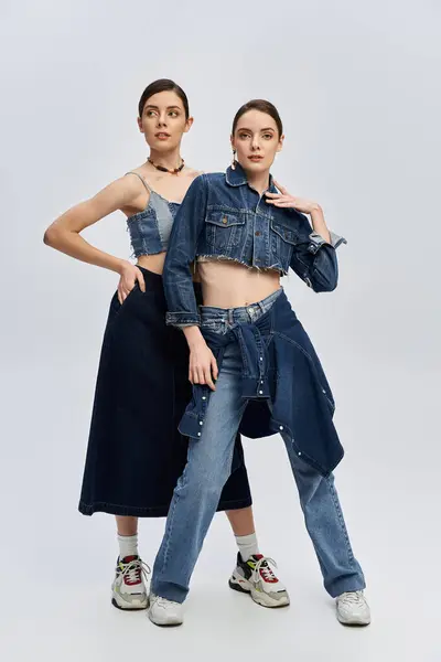 Sisters pose confidently in trendy denim ensembles with striking expressions and a fashionable flair — Stock Photo