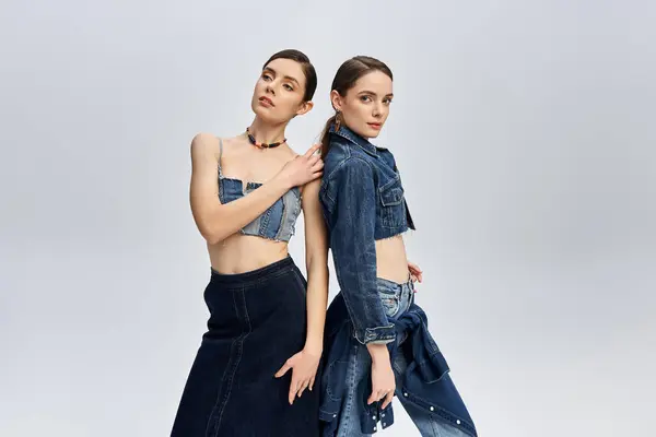 Two pretty sisters pose confidently in fashionable denim outfits, radiating beauty and style. — Stock Photo