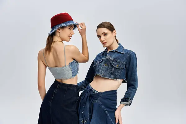Twin sisters pose elegantly, showcasing their stylish denim outfits and stunning looks. — Stock Photo