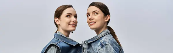 Two beautiful twin sisters smile brightly as they pose side by side, radiating happiness and style. — Stock Photo