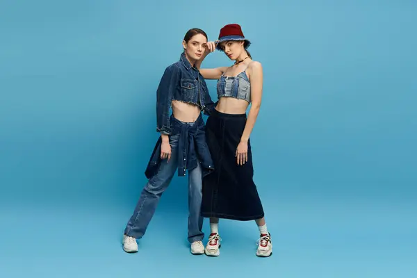 Des jumeaux élégants posent avec confiance, affichant leurs choix de mode denim tendance tout en partageant des sourires. — Photo de stock