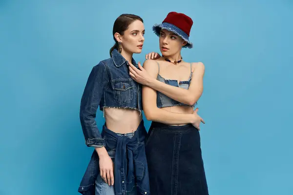 Two beautiful sisters stand together, showcasing their unique styles in trendy denim outfits. — Stock Photo