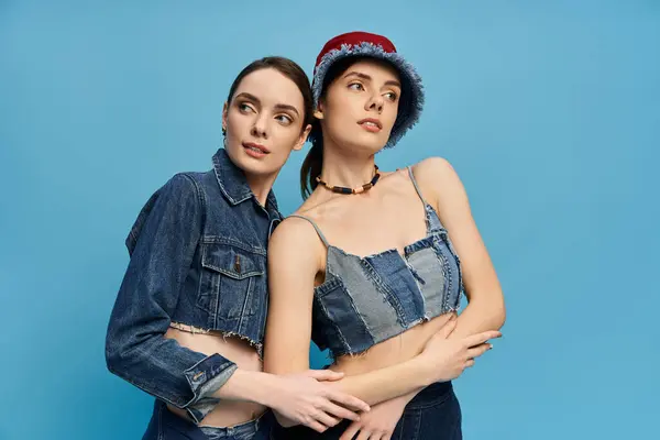 Two sisters pose playfully in matching outfits, showcasing their close bond and style. — Stock Photo