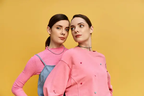 Twin sisters smile playfully while wearing colorful outfits in a lively and joyful setting. — Stock Photo