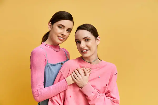 Deux jolies sœurs célèbrent leur lien avec des sourires, vêtues de vêtements élégants et de couleurs vives. — Photo de stock