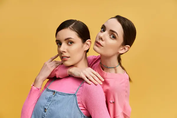 Two beautiful twins pose stylishly, radiating charm and connection in a bright setting. — Stock Photo