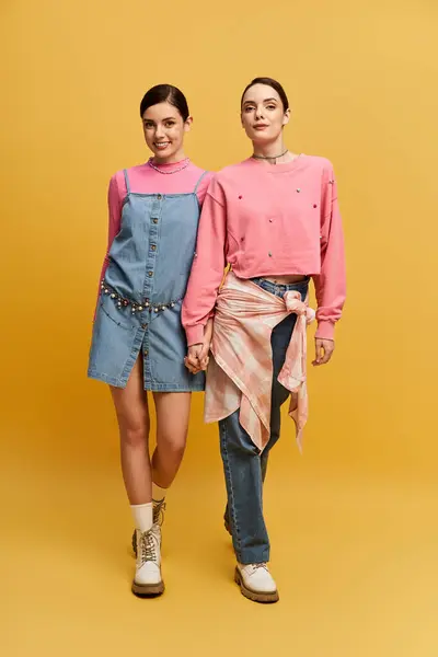 Two gorgeous twin sisters confidently showcase their unique, vibrant fashion styles. — Photo de stock