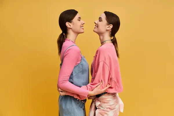 Two smiling sisters embrace, highlighting their close bond and stylish outfits. — Stock Photo