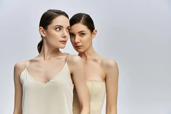 Two beautiful sisters stand closely together, showcasing their striking features and smooth skin. — Stock Photo