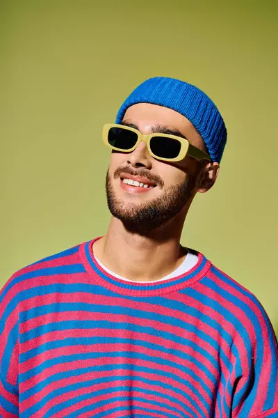 A young man in a colorful outfit radiates style and confidence against a bright green backdrop. — Stock Photo