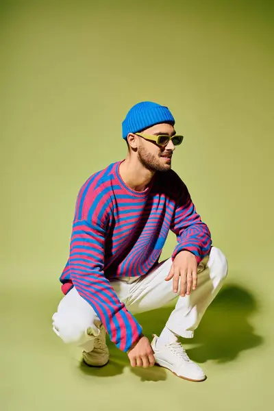 A young man in a stylish, colorful outfit poses confidently in a studio setting. — Stock Photo