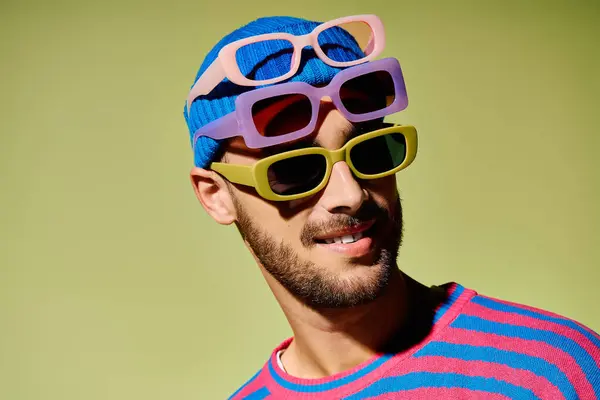 Un bel giovane uomo ostenta il suo senso della moda in un abito elegante, in mostra occhiali da sole alla moda. — Foto stock