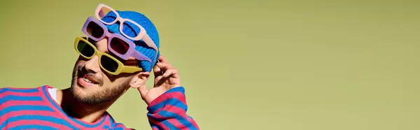 A young man flaunts his style in trendy sunglasses against a green studio background, banner — Stock Photo