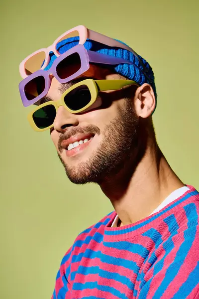 This stylish young man shows off his trendy sunglasses in a colorful studio. — Stock Photo