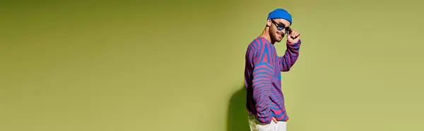 A young man showcases his style with vibrant sunglasses in a trendy studio setting, banner — Stock Photo