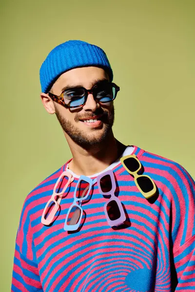 A young man displays his unique fashion sense, wearing trendy sunglasses with a colorful outfit. — Stock Photo