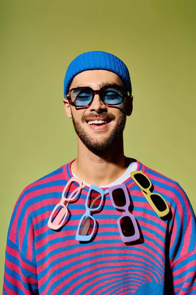 A young man shows off his style with sunglasses and a colorful outfit in a studio. — Stock Photo