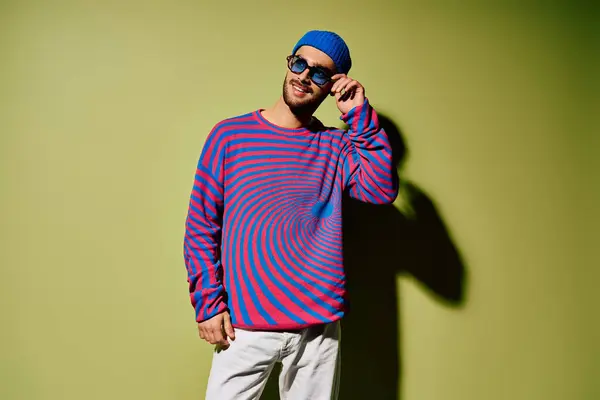 Stylish young man wearing trendy outfit and sunglasses poses confidently against a green backdrop. — Stock Photo