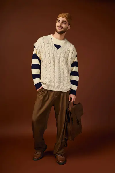 Jeune homme modèles tenue d'hiver à la mode et bonnet élégant sur fond marron. — Stock Photo