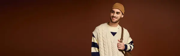 A handsome young man showcases his fashion sense in a studio setting with a brown backdrop. — Stock Photo