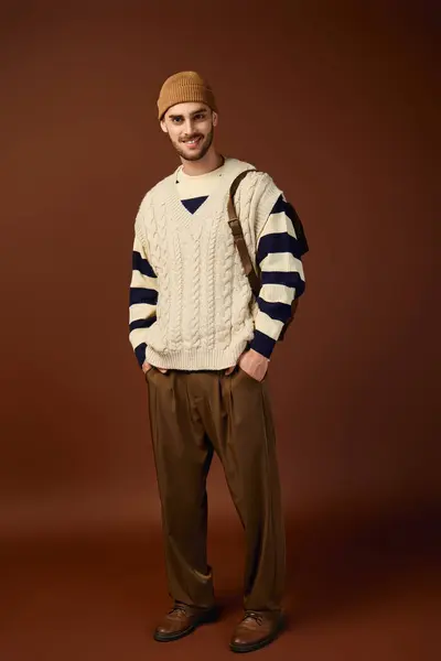 A stylish young man in a beanie poses confidently in a trendy studio. — Stock Photo