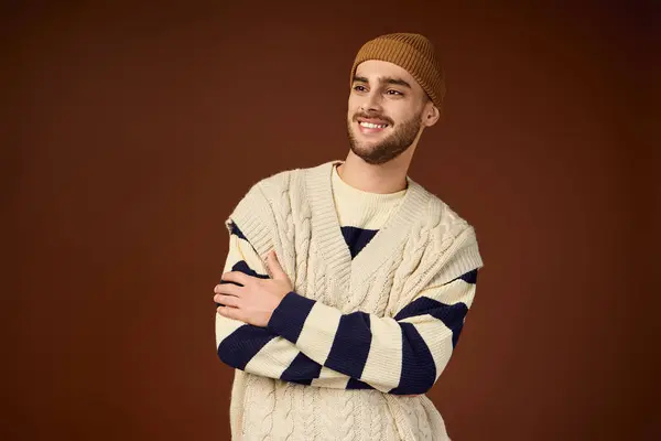 A handsome young man shows off his style in a cozy studio, wearing a trendy outfit and beanie. — Stock Photo