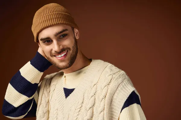 Handsome young man highlights his fashion sense wearing a knitted beanie and sweater in studio. — Stock Photo
